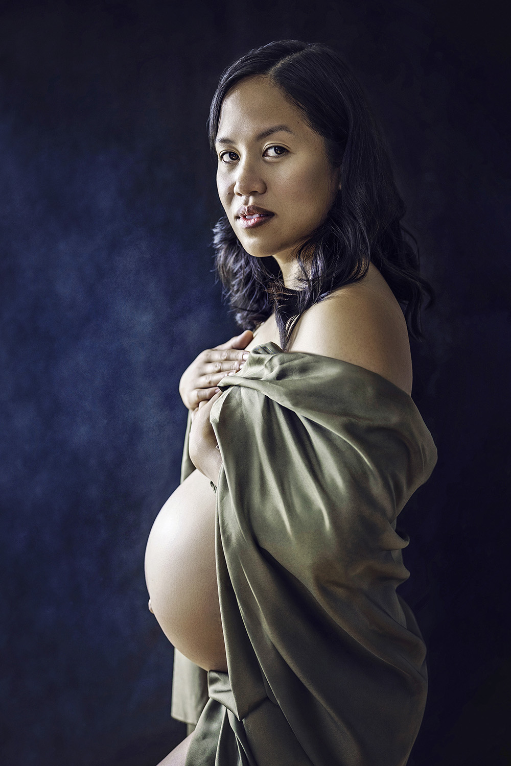 gravide unge kvinner dekket med en grønn silke tøystykker på en blå bakgrunn