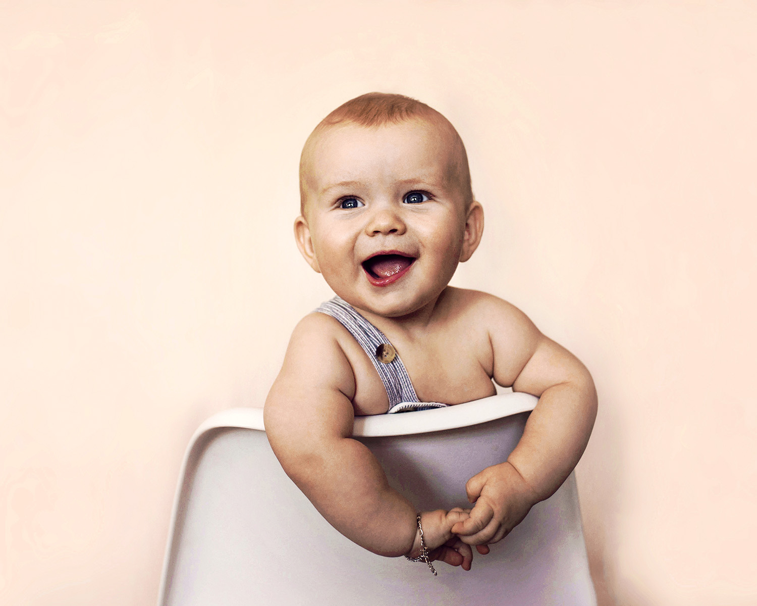 baby sitter på en hvit stol med et stort smil